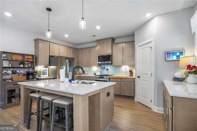 kitchen featuring tasteful backsplash, light wood-type flooring, appliances with stainless steel finishes, and a sink