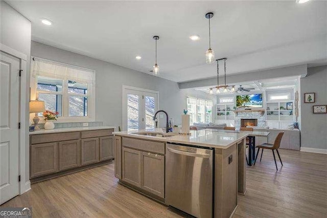 kitchen with dishwasher, a fireplace, light wood-type flooring, and a sink