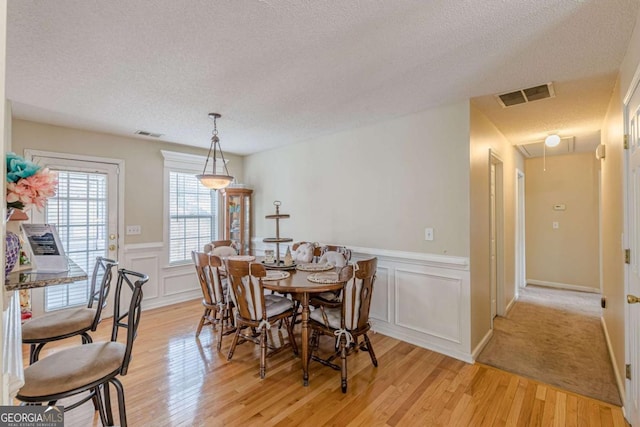 dining room with light wood-type flooring, visible vents, and attic access