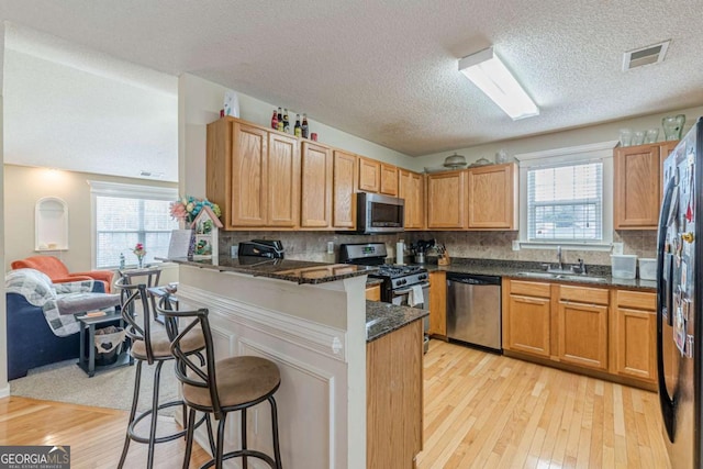 kitchen with a breakfast bar area, visible vents, a peninsula, a sink, and appliances with stainless steel finishes