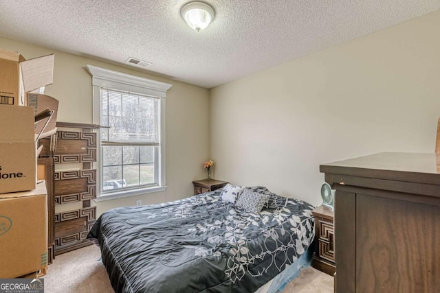 bedroom with carpet flooring, visible vents, and a textured ceiling