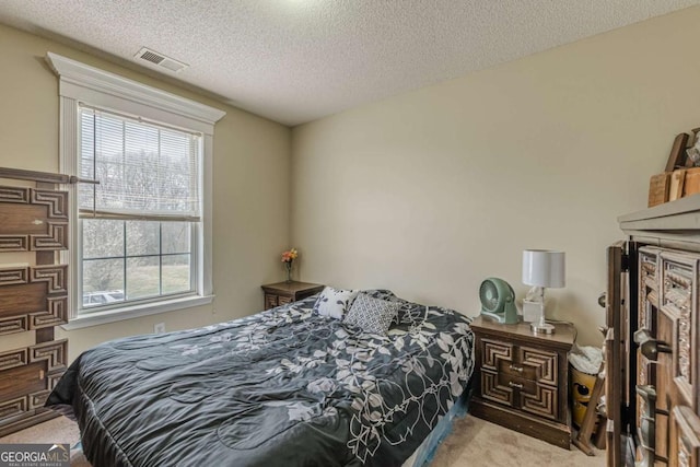 bedroom with carpet, visible vents, and a textured ceiling