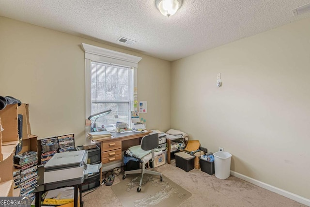 home office with a textured ceiling, carpet, visible vents, and baseboards