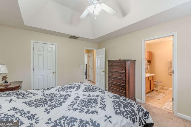 bedroom with visible vents, baseboards, a tray ceiling, light colored carpet, and connected bathroom