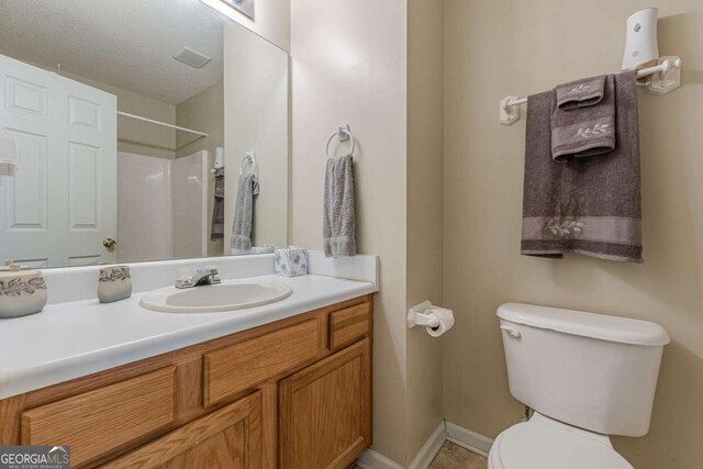 full bathroom with baseboards, toilet, walk in shower, and vanity