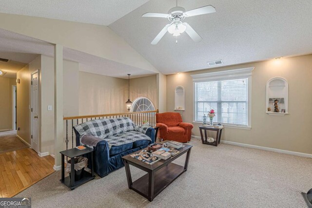 carpeted living area with vaulted ceiling, baseboards, visible vents, and ceiling fan