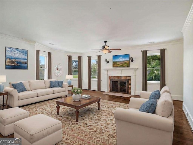 living room featuring baseboards, ornamental molding, a fireplace, wood finished floors, and a ceiling fan