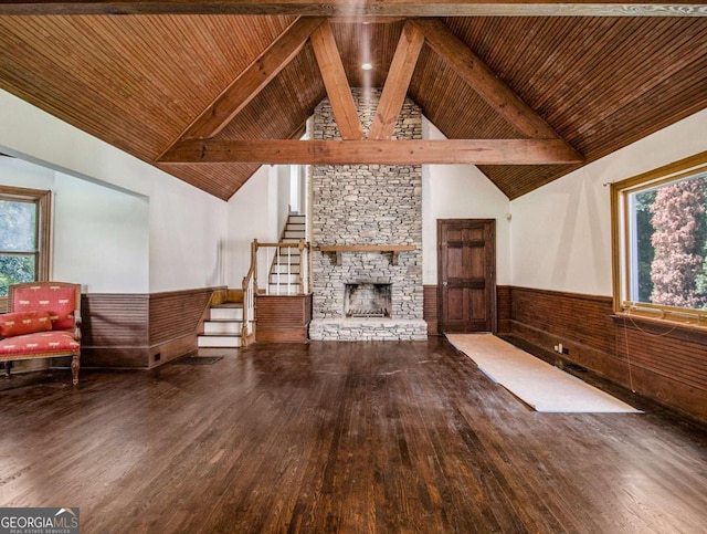 unfurnished living room with wooden ceiling, a stone fireplace, hardwood / wood-style floors, and wainscoting