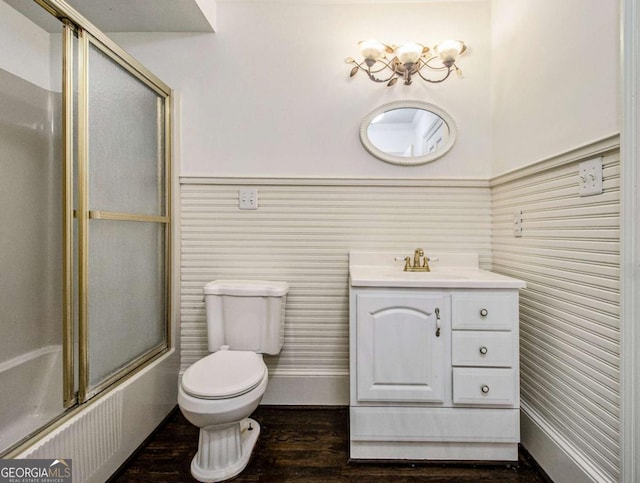 bathroom featuring bath / shower combo with glass door, toilet, wood finished floors, and vanity