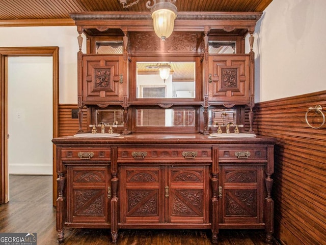 bar with a sink, a wainscoted wall, dark wood-type flooring, and wood ceiling