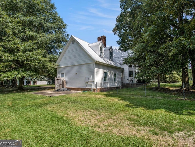 rear view of house featuring metal roof, a lawn, a chimney, and fence