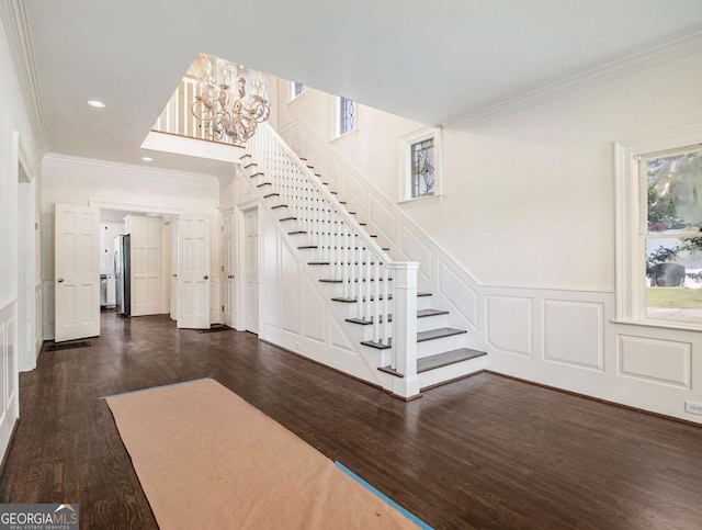 stairway with crown molding, a decorative wall, wood finished floors, and wainscoting