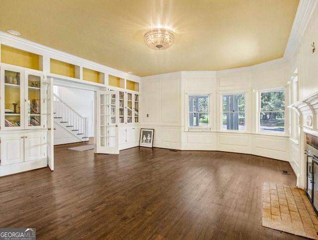 interior space featuring built in shelves, stairs, a tile fireplace, wood finished floors, and a decorative wall