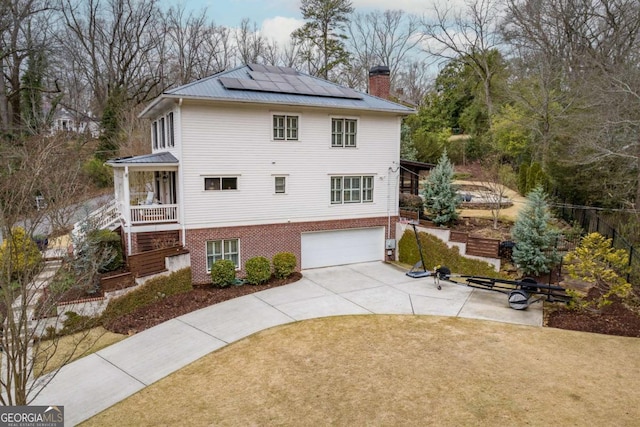 exterior space with brick siding, solar panels, a front yard, a chimney, and metal roof