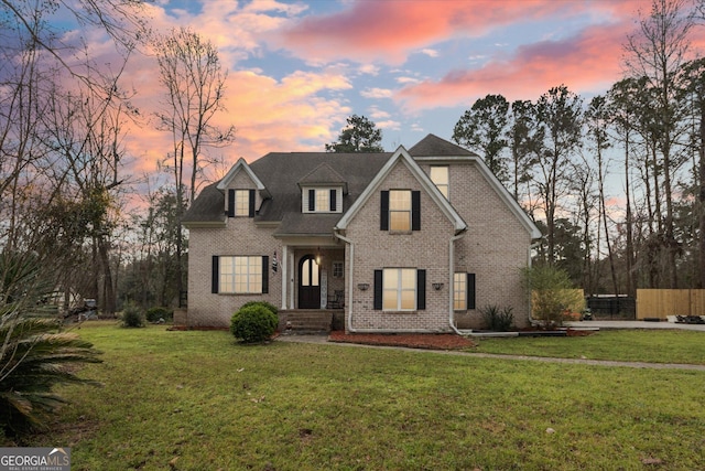 view of front of house with brick siding and a yard