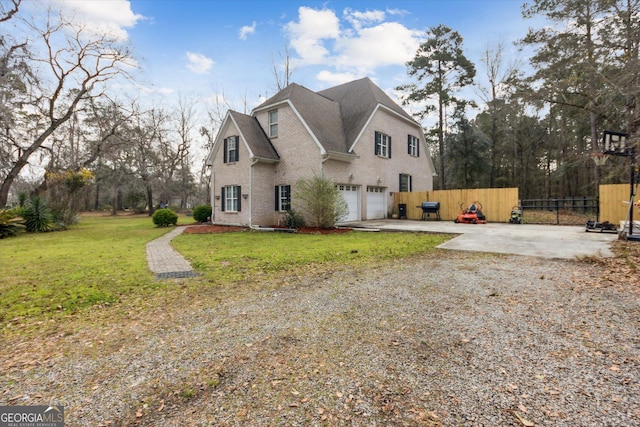 view of side of home with brick siding, an attached garage, fence, a lawn, and driveway