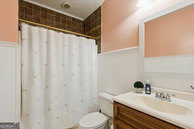 bathroom featuring toilet, vanity, wainscoting, a shower with curtain, and a textured ceiling