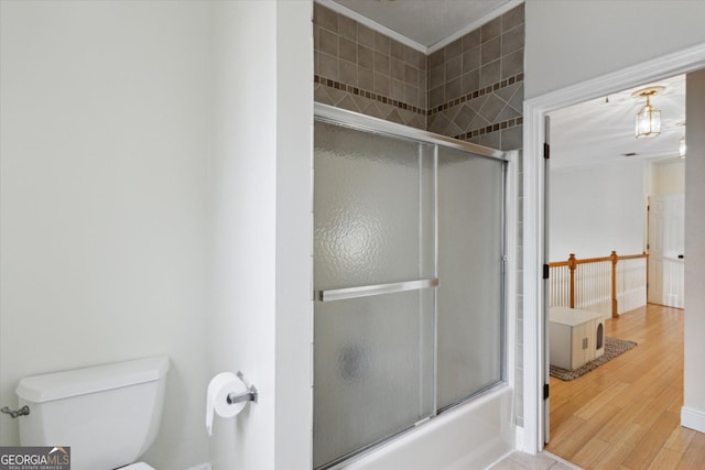 full bath featuring wood finished floors, toilet, and shower / bath combination with glass door