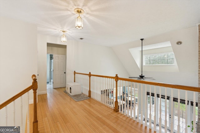 corridor featuring lofted ceiling, an upstairs landing, and light wood-style floors