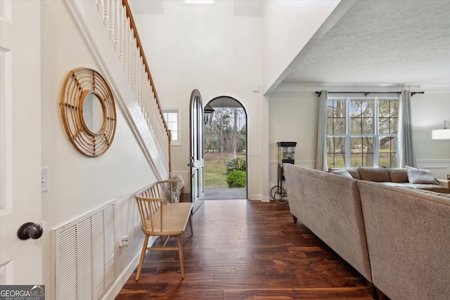 entryway featuring visible vents, dark wood-type flooring, baseboards, stairs, and a towering ceiling