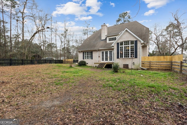 back of house with brick siding, entry steps, french doors, a chimney, and a fenced backyard