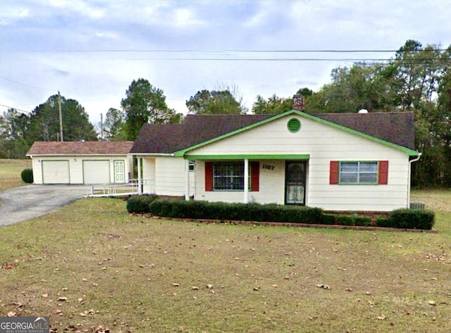 ranch-style house with an outbuilding, a front yard, aphalt driveway, and a garage