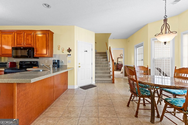 kitchen featuring black appliances, a sink, backsplash, brown cabinetry, and light tile patterned floors