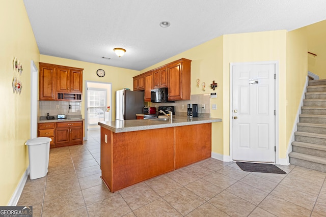 kitchen featuring a peninsula, freestanding refrigerator, electric range oven, light countertops, and black microwave