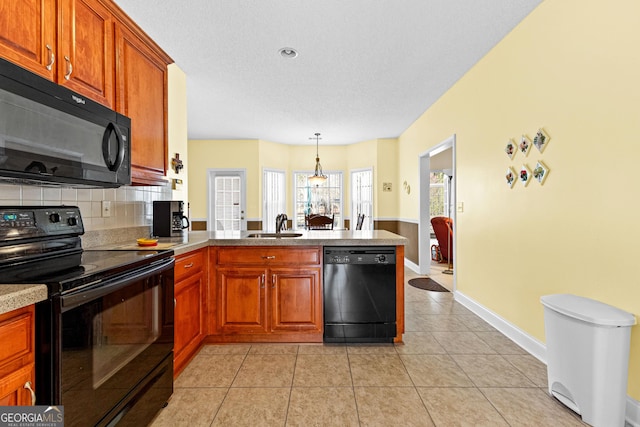 kitchen featuring black appliances, a sink, tasteful backsplash, a peninsula, and light tile patterned floors