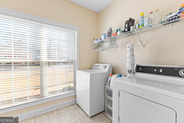 clothes washing area with washer and dryer, light tile patterned flooring, and laundry area