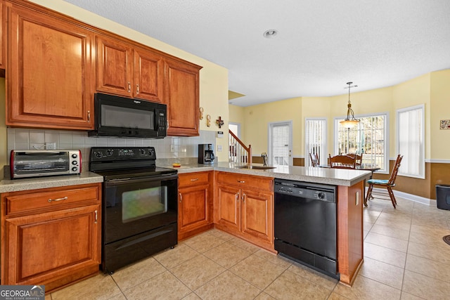 kitchen with black appliances, a toaster, a peninsula, brown cabinetry, and light countertops