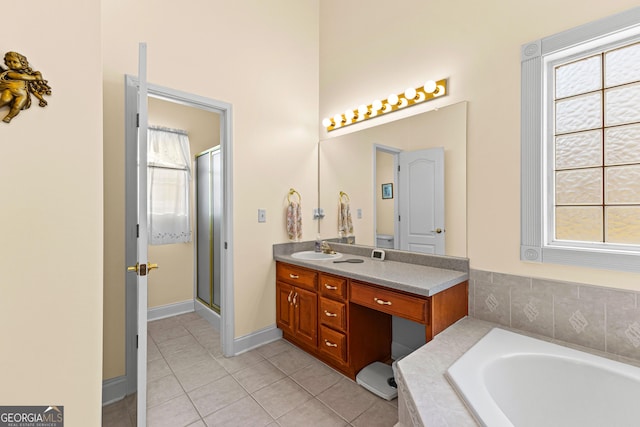 full bathroom with tile patterned flooring, baseboards, a stall shower, a bath, and vanity