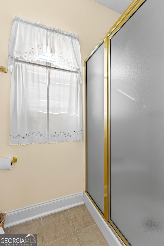 bathroom with tile patterned flooring, a shower stall, and baseboards