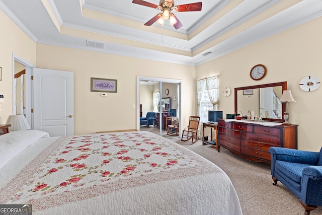 carpeted bedroom featuring visible vents, a tray ceiling, and ornamental molding