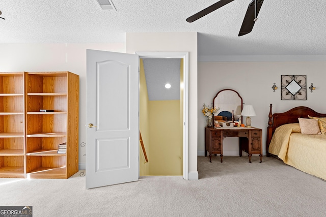 carpeted bedroom with visible vents, a textured ceiling, and a ceiling fan