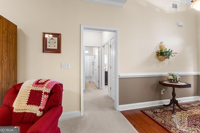 hall with visible vents, baseboards, and wood finished floors