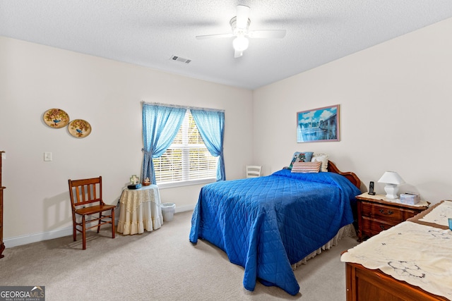 bedroom with baseboards, light colored carpet, visible vents, and a textured ceiling