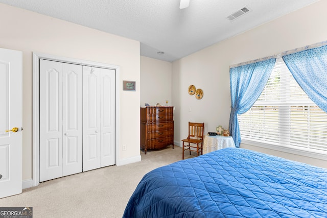 bedroom with visible vents, carpet flooring, a closet, a textured ceiling, and a ceiling fan