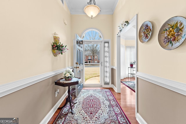 doorway to outside featuring visible vents, baseboards, wood finished floors, and ornamental molding