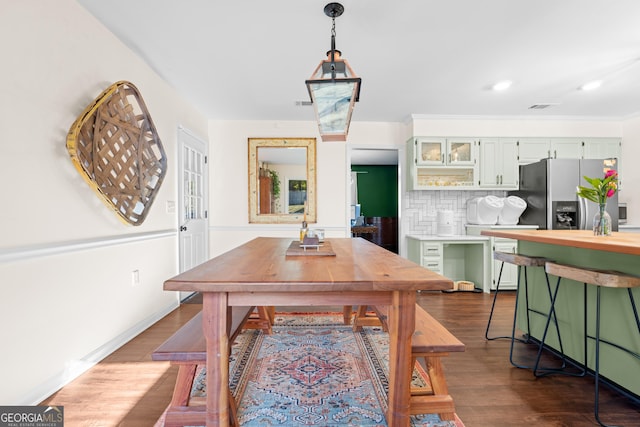 dining space featuring dark wood finished floors, crown molding, recessed lighting, and baseboards