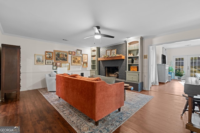 living area with visible vents, a brick fireplace, crown molding, dark wood finished floors, and french doors