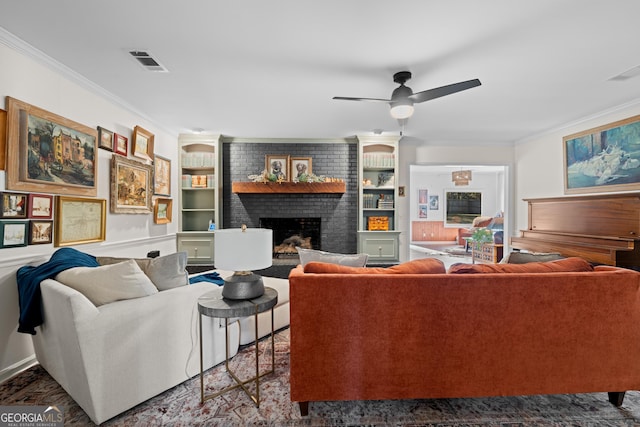 living room featuring visible vents, a brick fireplace, crown molding, and built in features