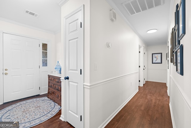 hallway featuring dark wood finished floors, crown molding, baseboards, and visible vents