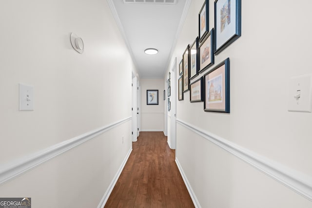 hall with dark wood-style floors, visible vents, crown molding, and baseboards