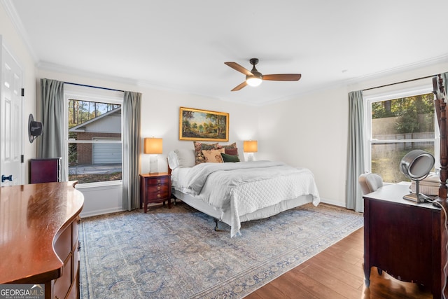 bedroom with multiple windows, crown molding, a ceiling fan, and wood finished floors