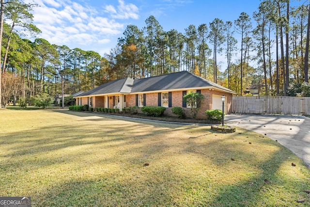 view of front facade with brick siding, driveway, a front yard, and fence