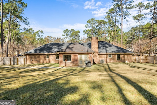 back of property with french doors, a yard, and fence