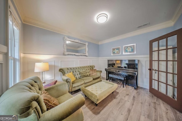 living room featuring visible vents, wood finished floors, wainscoting, and ornamental molding