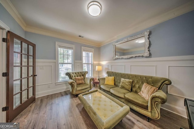 living area featuring visible vents, crown molding, a wainscoted wall, and wood finished floors