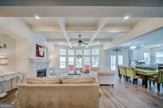 living area featuring coffered ceiling, beamed ceiling, a fireplace, and light wood-type flooring